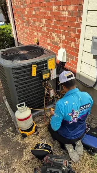 Technician servicing an outdoor air conditioner with gauges and tools